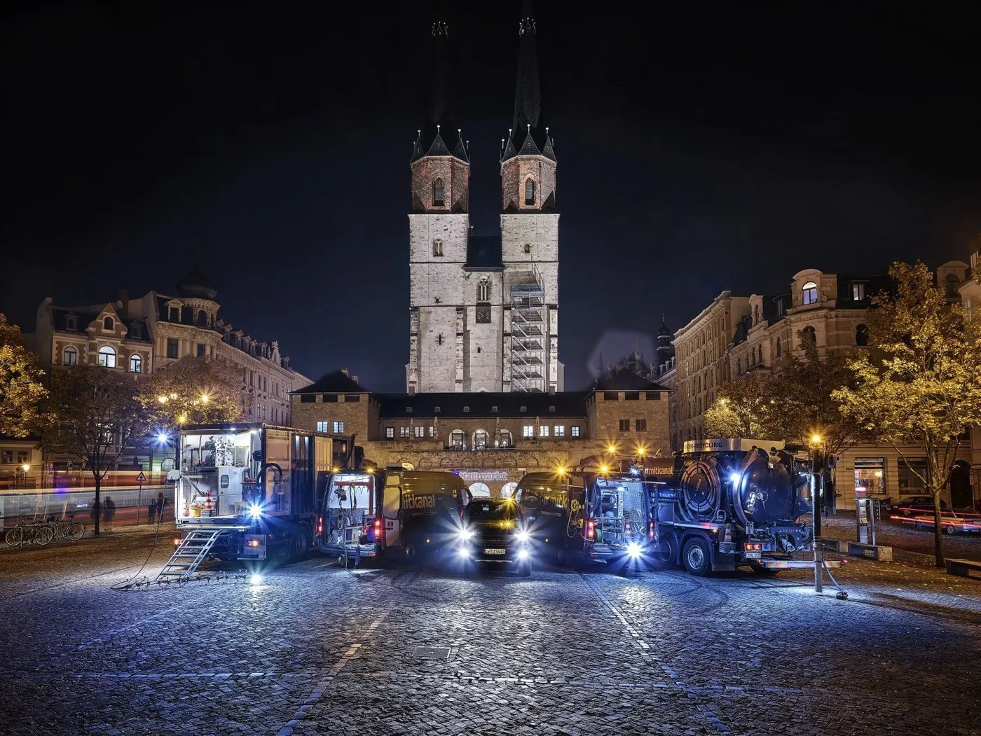 KSG service vehicles lined up at a night-time job in a city square
