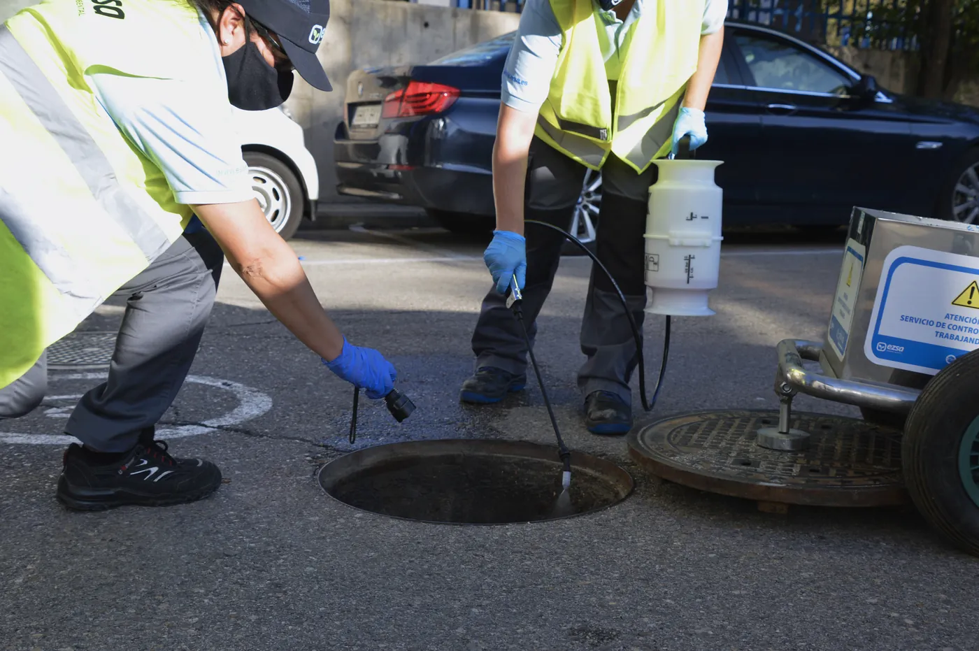 Technicians treating a sewer manhole against pests