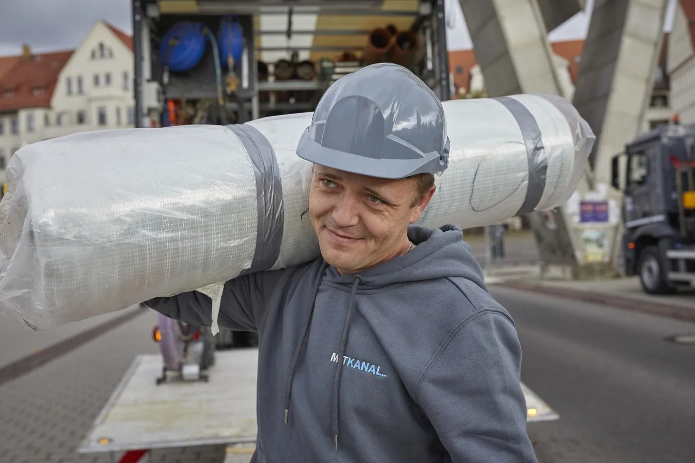 Specialist carrying a sewer liner on a city job site