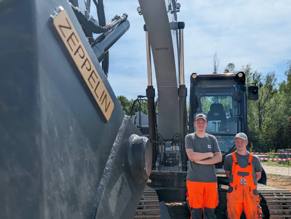 Two operators in front of their excavator