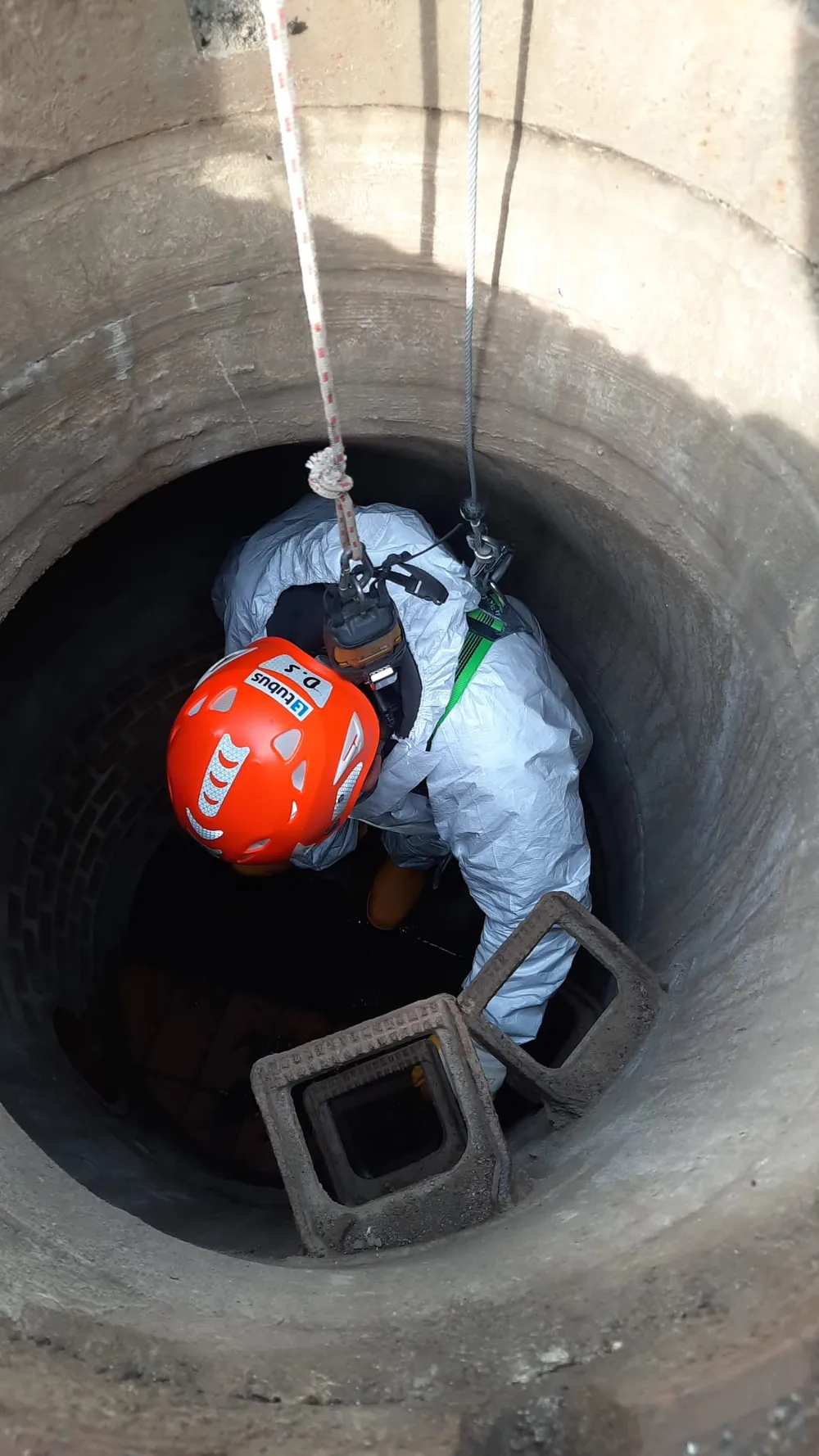 Specialist descending into a manhole