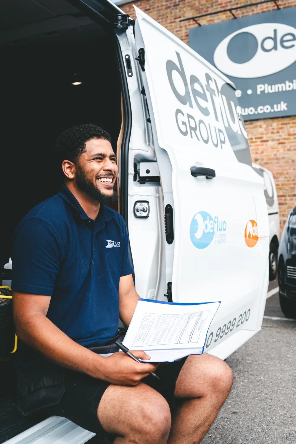Smiling Defluo engineer with his paperwork at the van