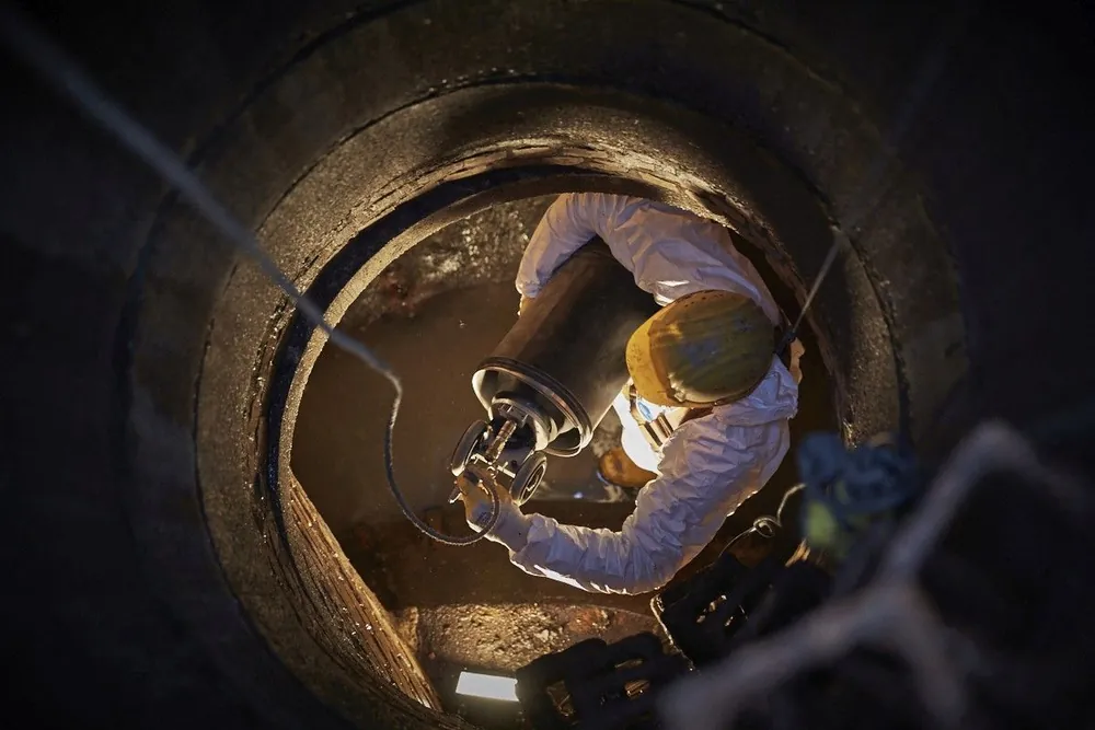 Specialist working deep inside a manhole