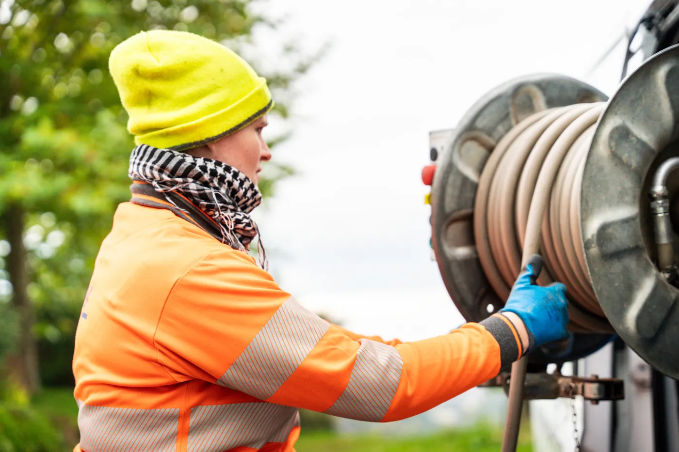 Specialist in high-visibility gear and gloves handling a hose reel