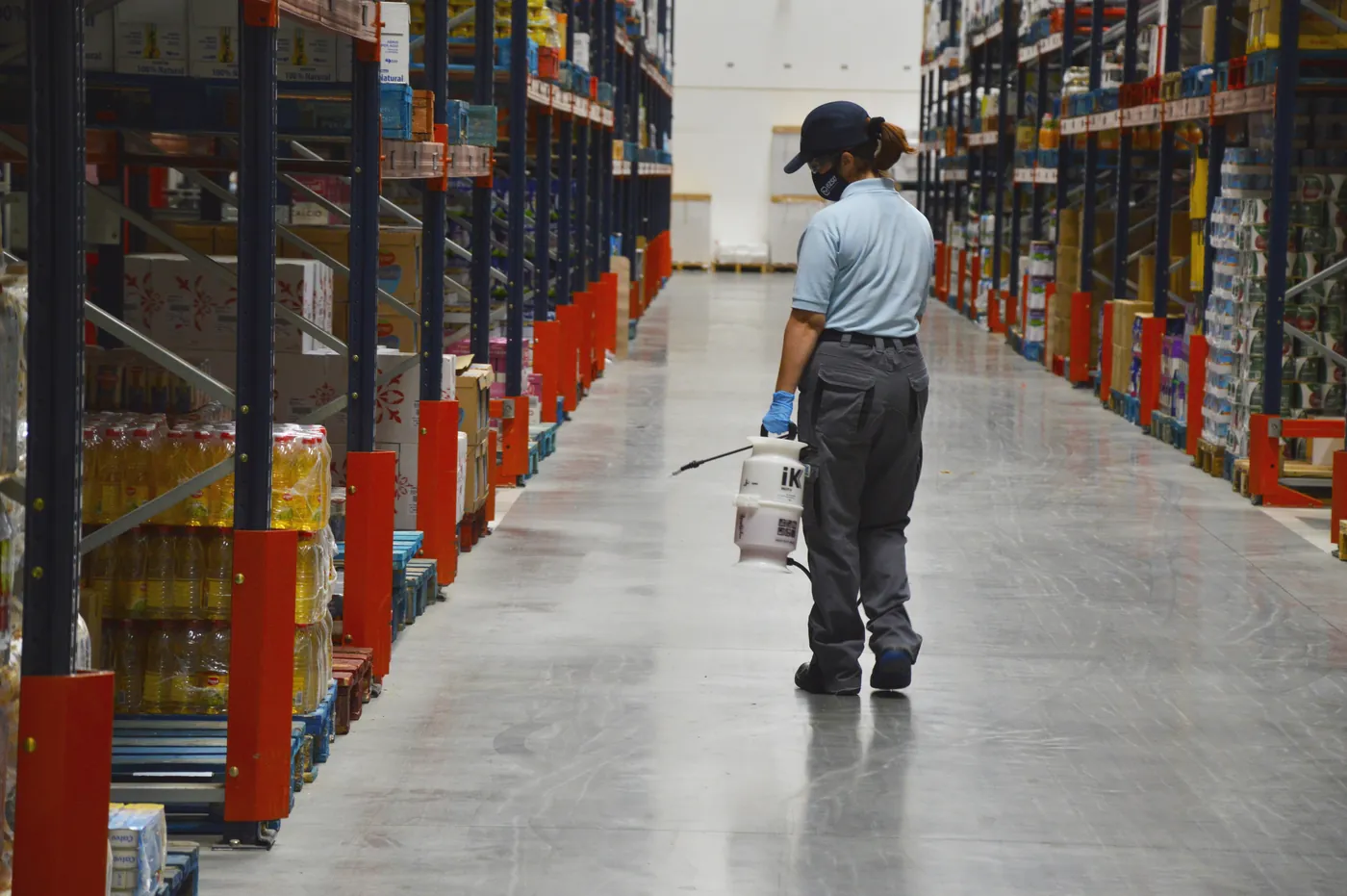 Technician disinfecting a warehouse aisle