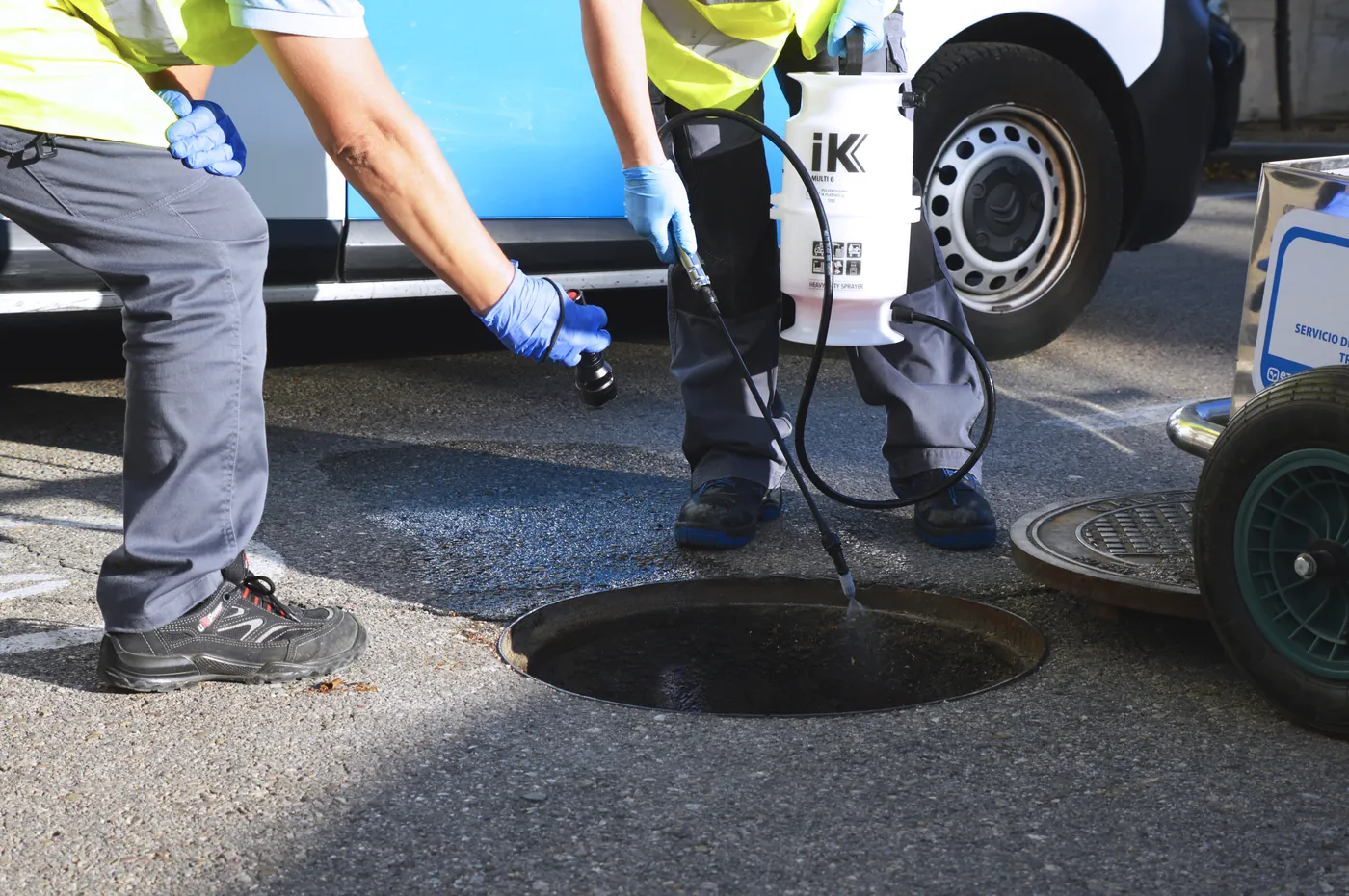 Technicians applying a pest treatment in a sewer manhole