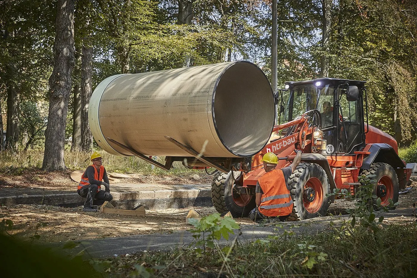 Crew placing a large sewer pipe with a wheel loader